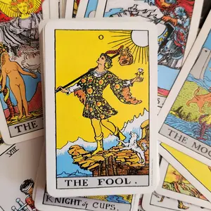 A photographic image of The Fool, card zero, from the Rider-Waite-Smith tarot deck. The background is the other cards scattered around.