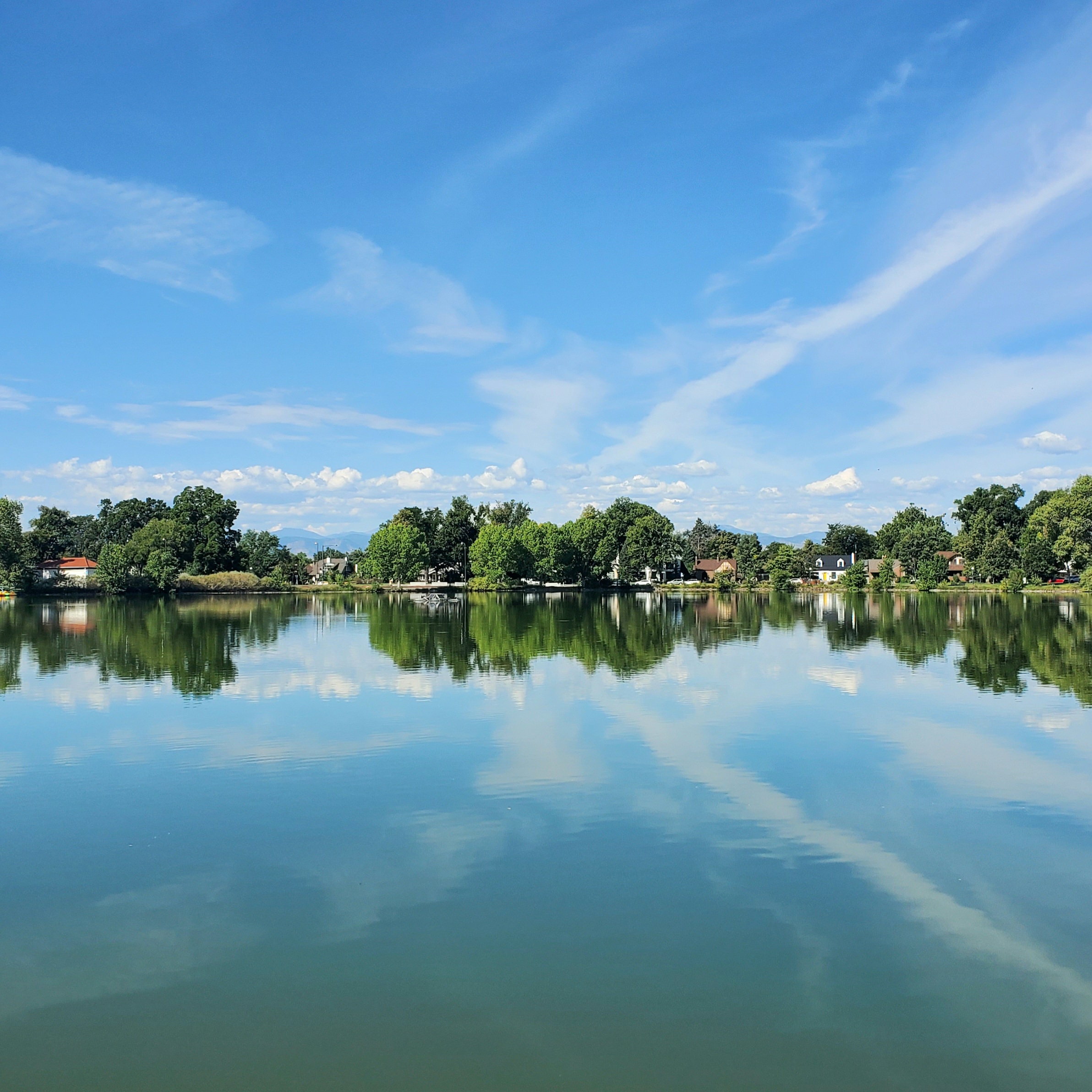 A calm lake on a sunny day reflecting the trees and sky.