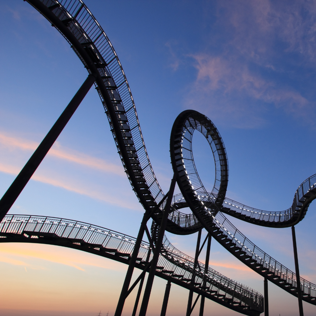 An image of a winding roller coaster on a backdrop of an evening sky.