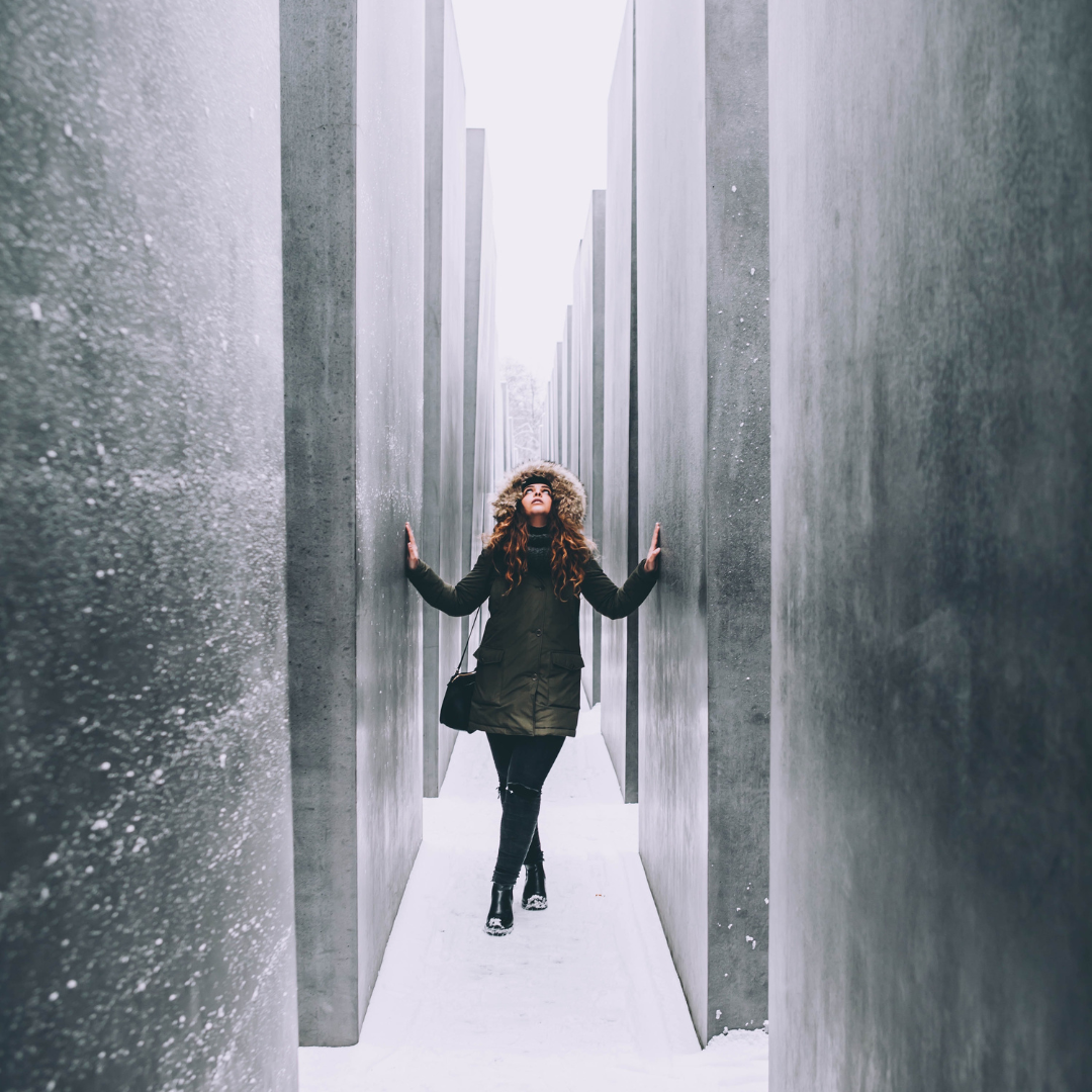 A woman standing in the snow between two smooth stone walls.