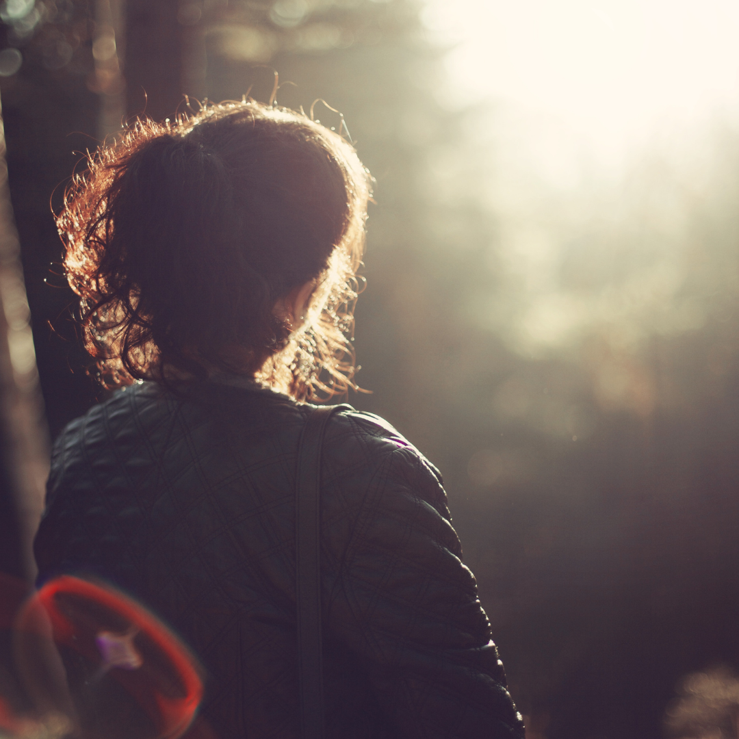 An image of someone emerging from the dark into the light.