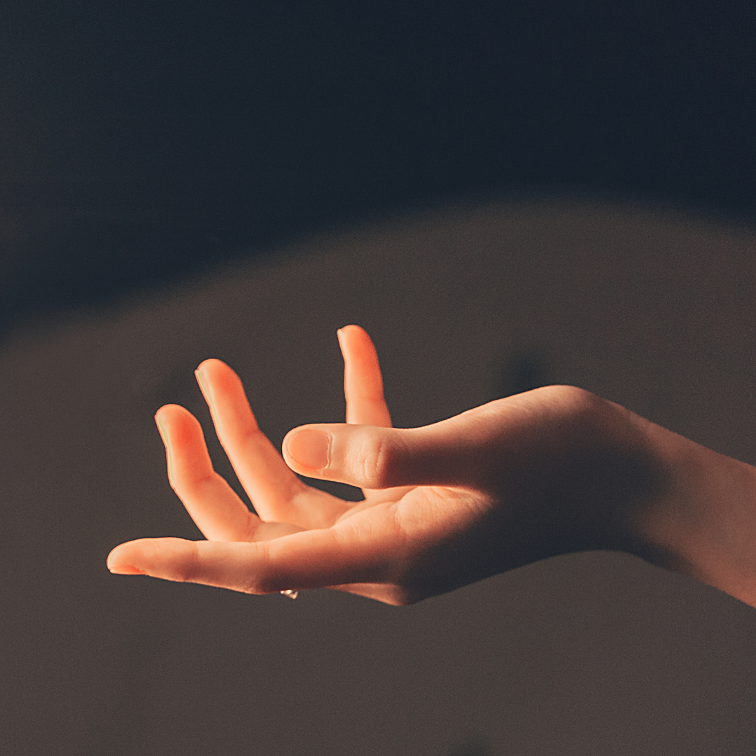 The image is of a softly open hand, spotlighted on a dark background.