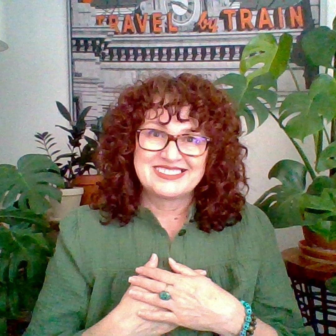 An image of me. I am sitting in the living room of the apartment I had last year. My arms hands are together over my heart. My face is shining brightly with Divine love and light. This image was used on my YouTube channel I felt spiritually empowered.